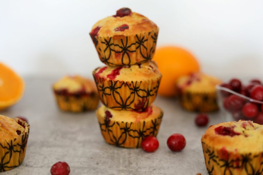 Stack of cranberry orange muffins with orange in the background