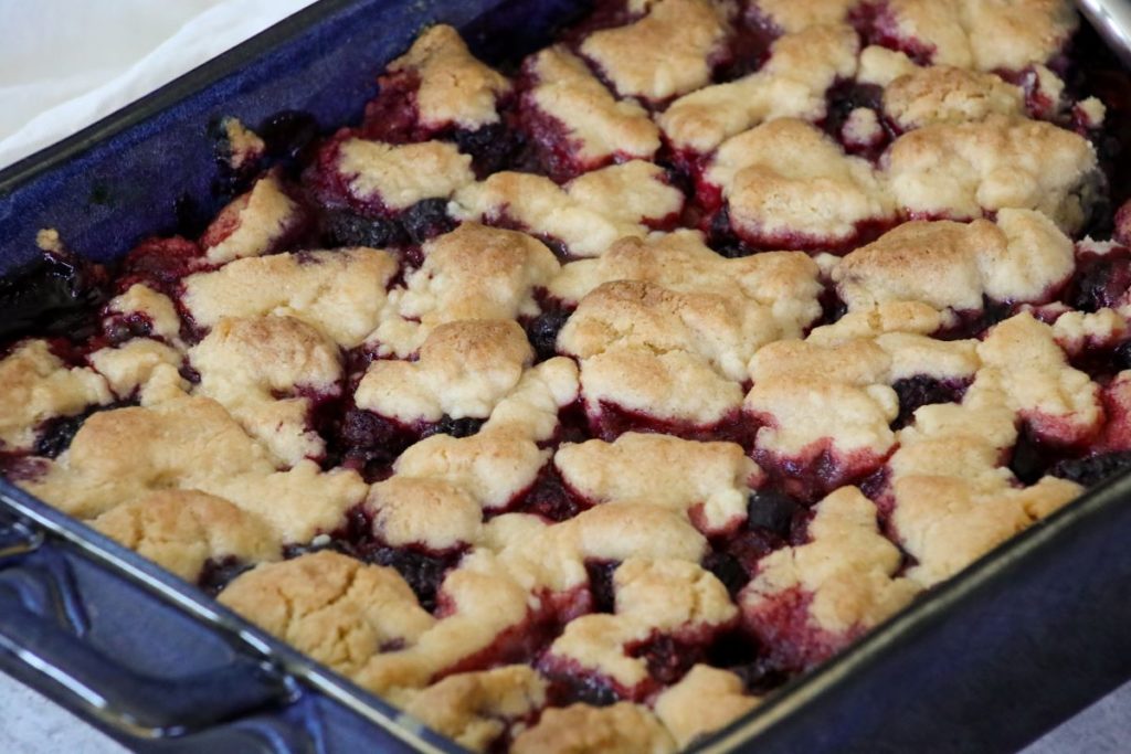 close up of a baked berry cobbler in a blue baking dish