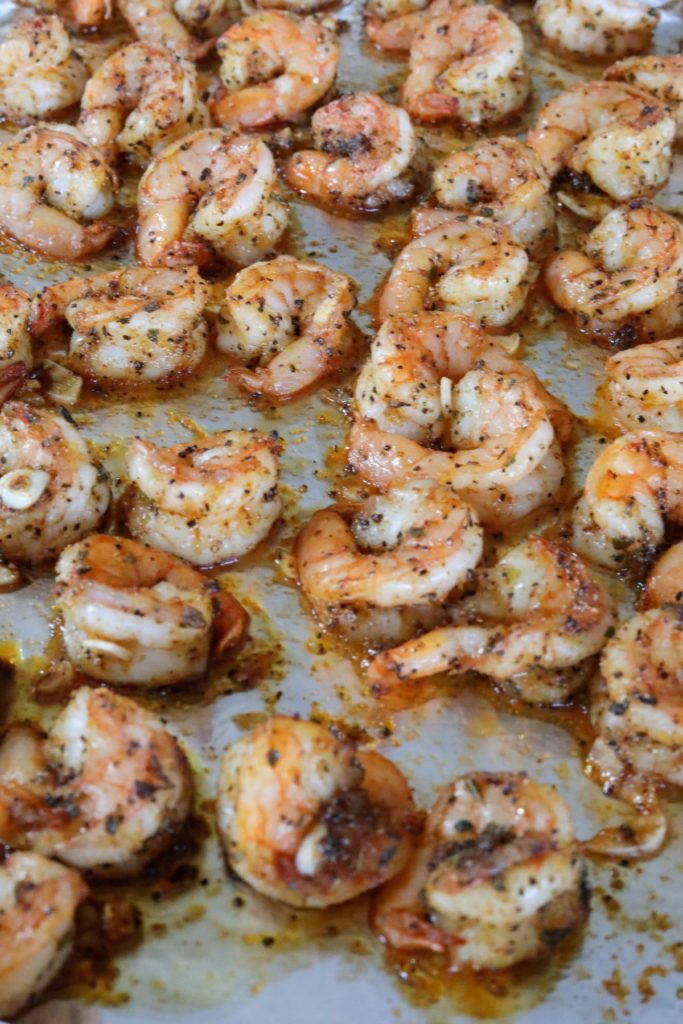 A foil lined sheet pan with cooked blackened shrimp with garlic