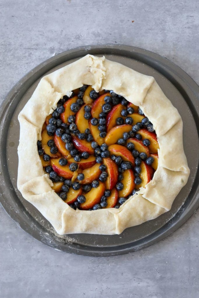blueberry peach galette with crust folded over before baking.