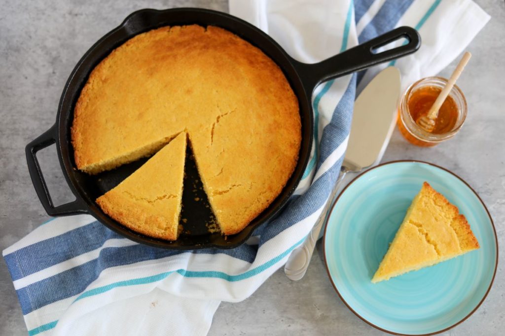 Cornbread in a cast iron skillet and on a blue plate