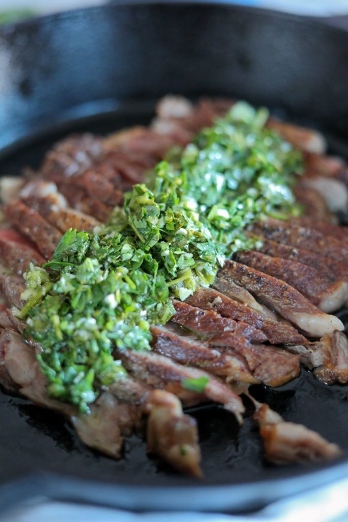 close up of sliced pan seared steak with chimichurri sauce