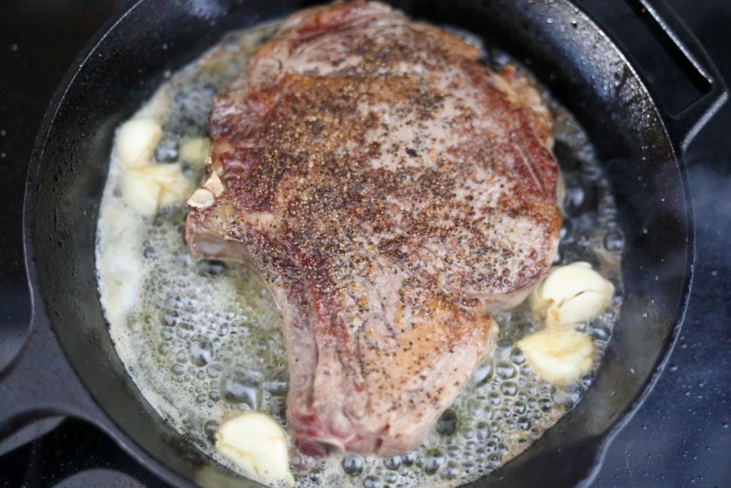 seared steak with garlic and butter in a cast iron skillet