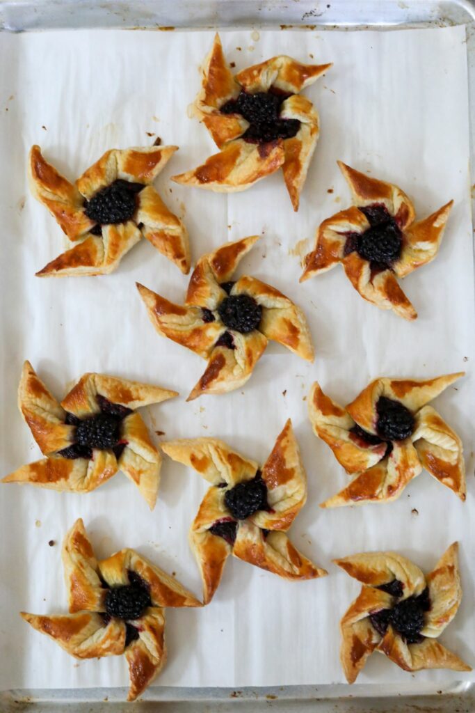 Baked blackberry pinwheels on a parchment lined sheet pan