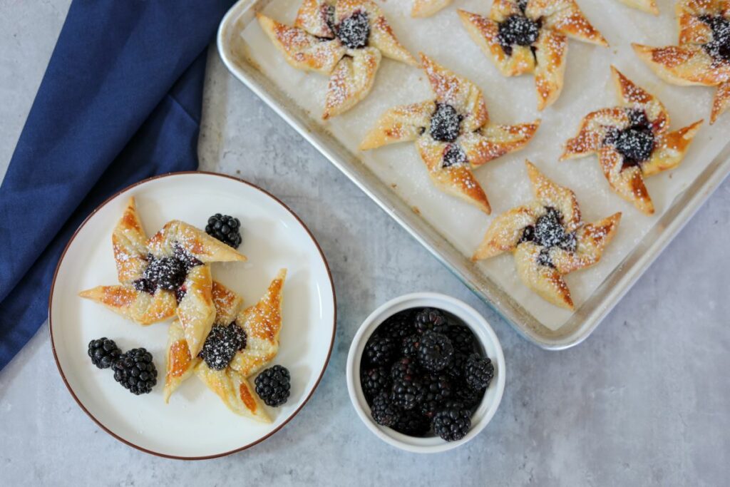 Blackberry pinwheels on a white plate with a bowl of blackberries