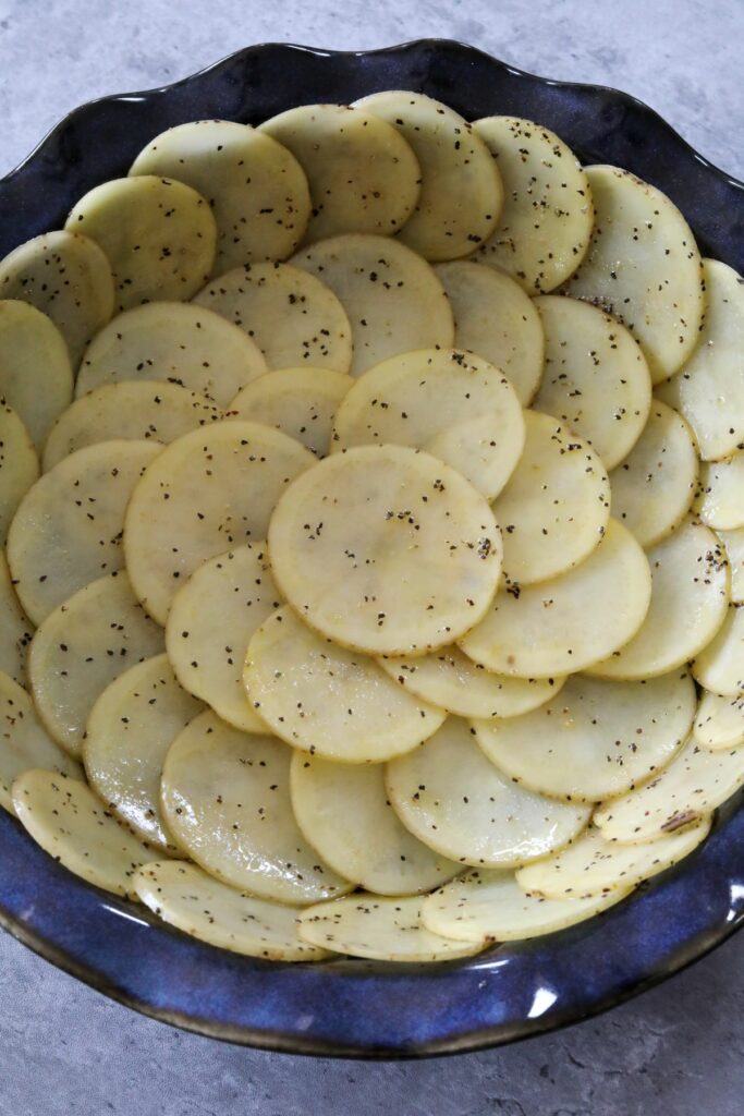 Uncooked potato crust in a blue pie dish