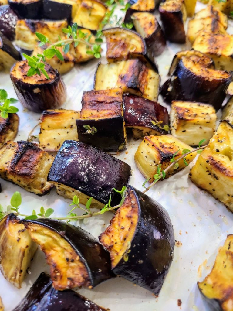 roasted eggplant on a lined sheet pan with sprigs of thyme
