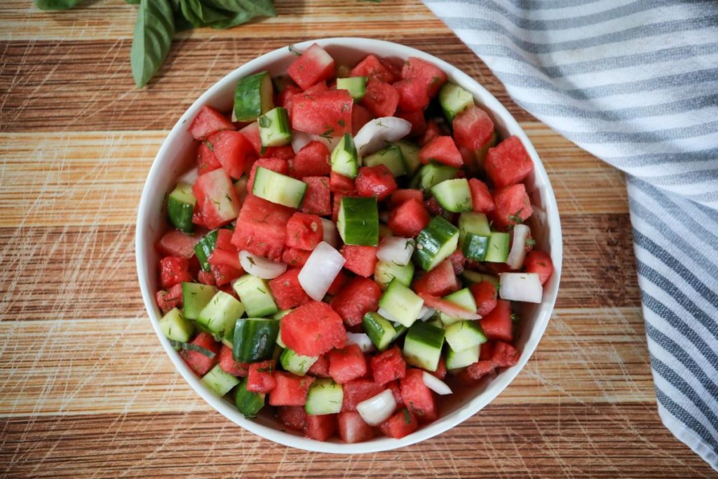 Watermelon salad in a white bowl on a cutting boar