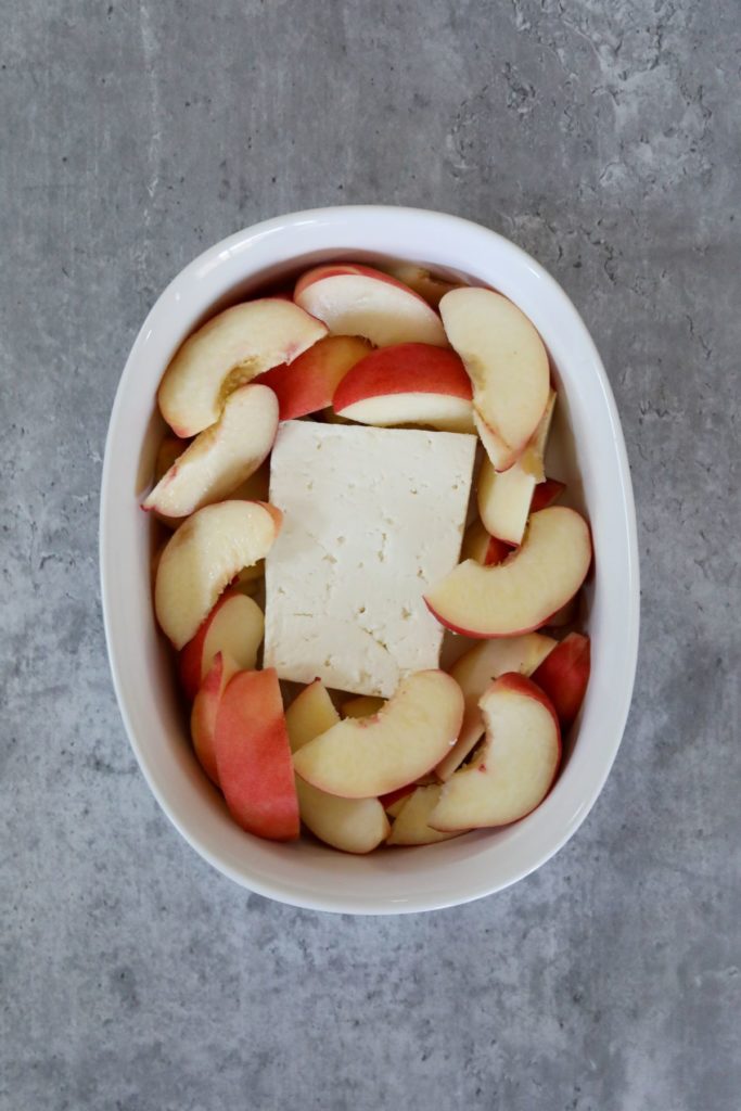 Unbaked feta and peach slices in a baking dish