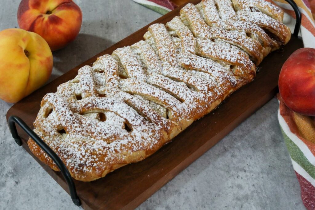 peach strudel on a wooden serving tray on a towel
