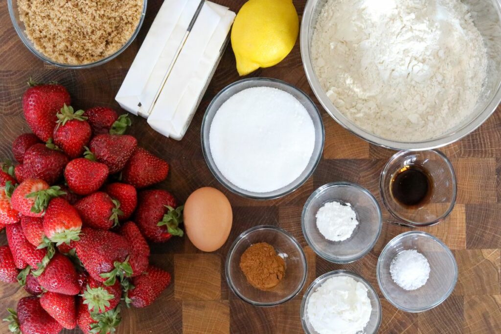 Ingredients for strawberry crumble bars on a wooden cutting board