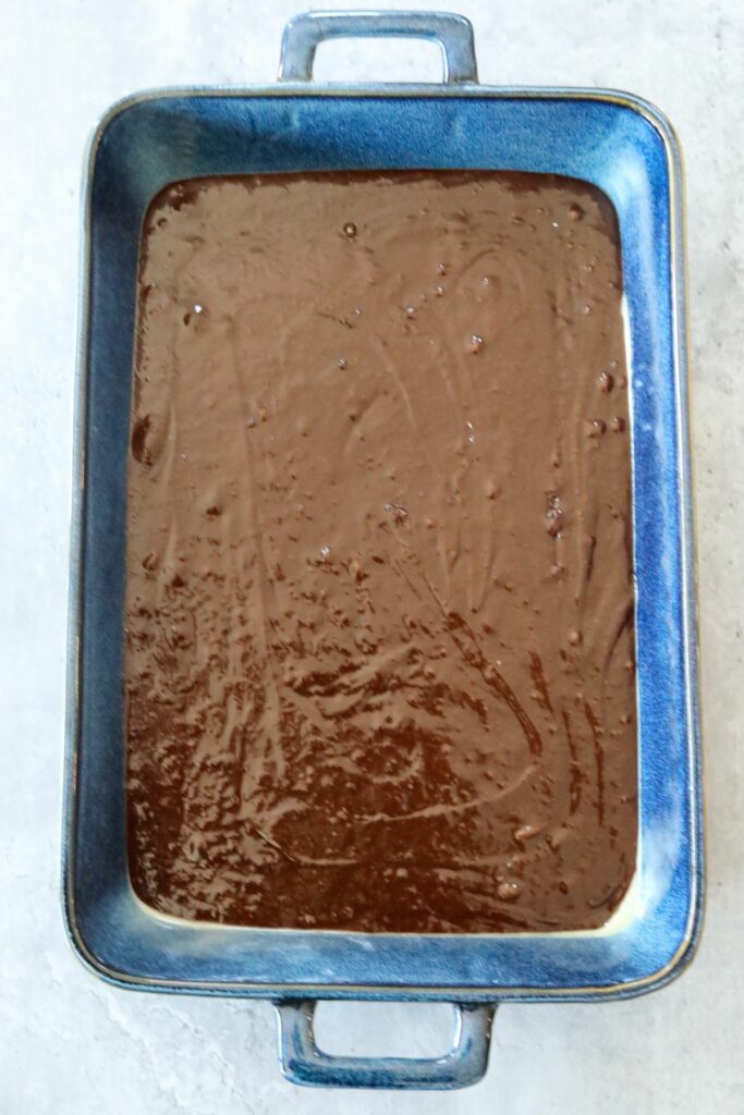 uncooked brownie batter in a blue baking dish