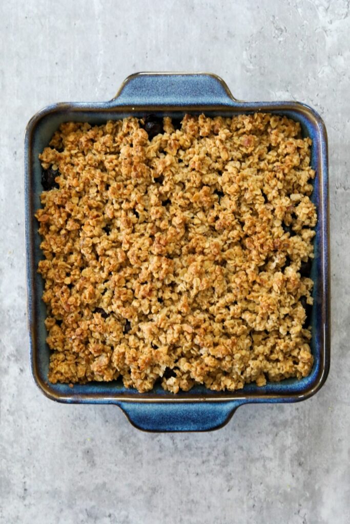 Cooked blueberry crisp in a blue baking dish