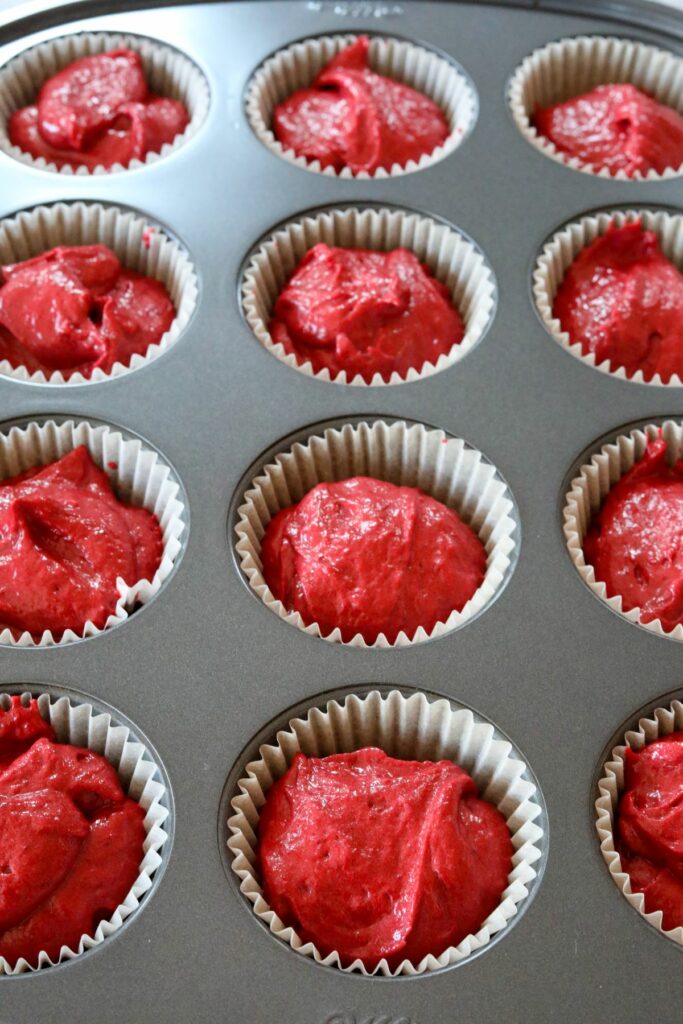 Uncooked red velvet cupcake batter in a lined muffin tin