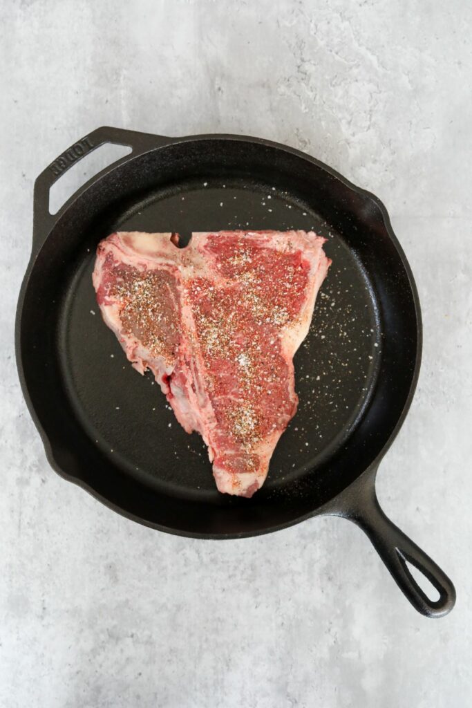 Uncooked steak in a cast iron skillet