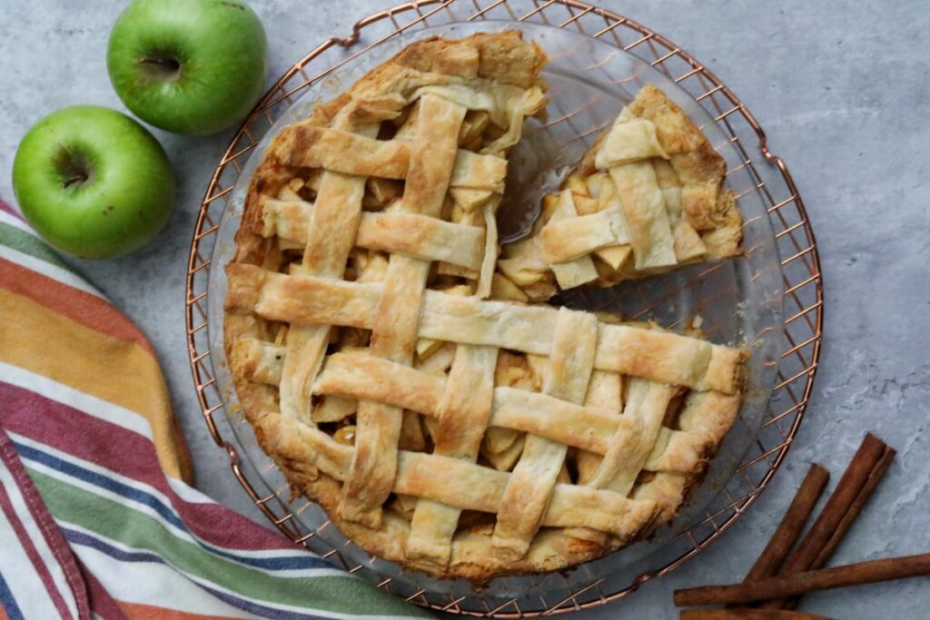 Apple pie in baking dish with a slice removed