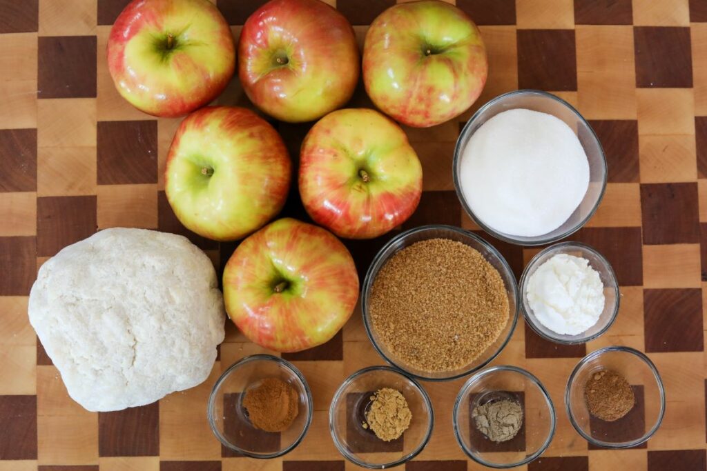 apple pie ingredients on a wooden cutting board