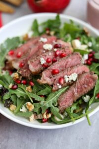 A serving of pomegranate and steak salad in a white dish