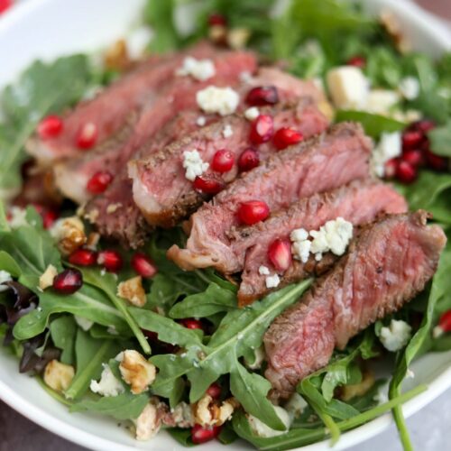 A serving of pomegranate and steak salad in a white dish