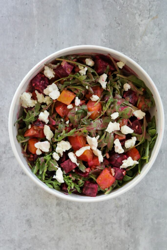 A dressed roasted beet salad in a white bowl