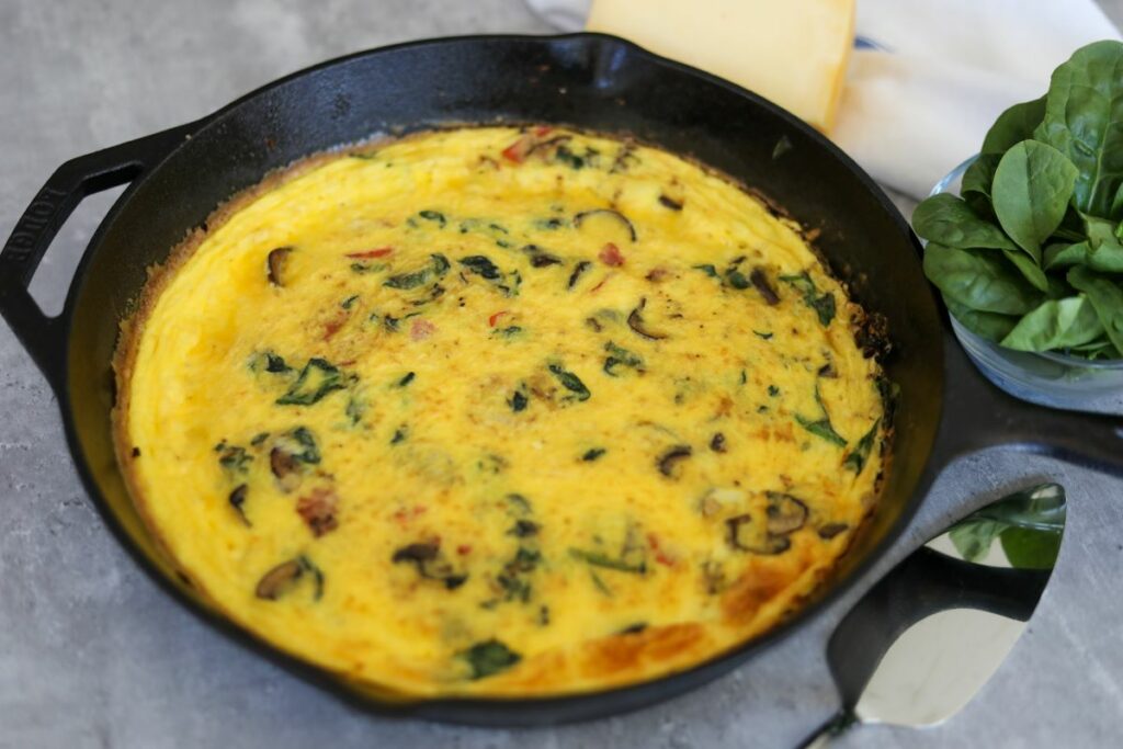 Close up of a spinach and mushroom frittata in a cast iron skillet