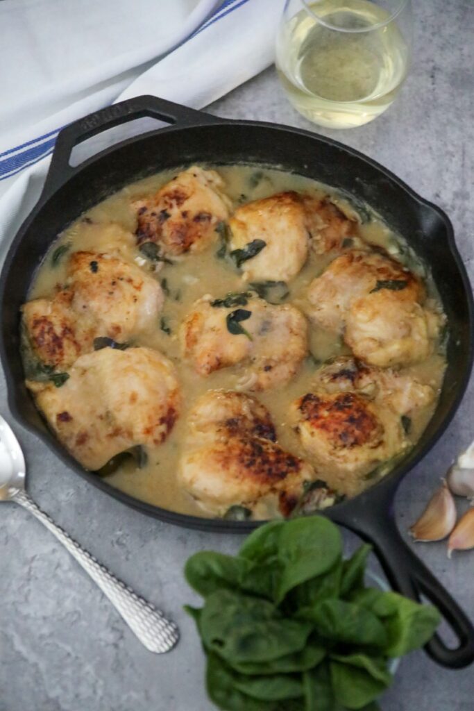 A skillet with chicken in white wine