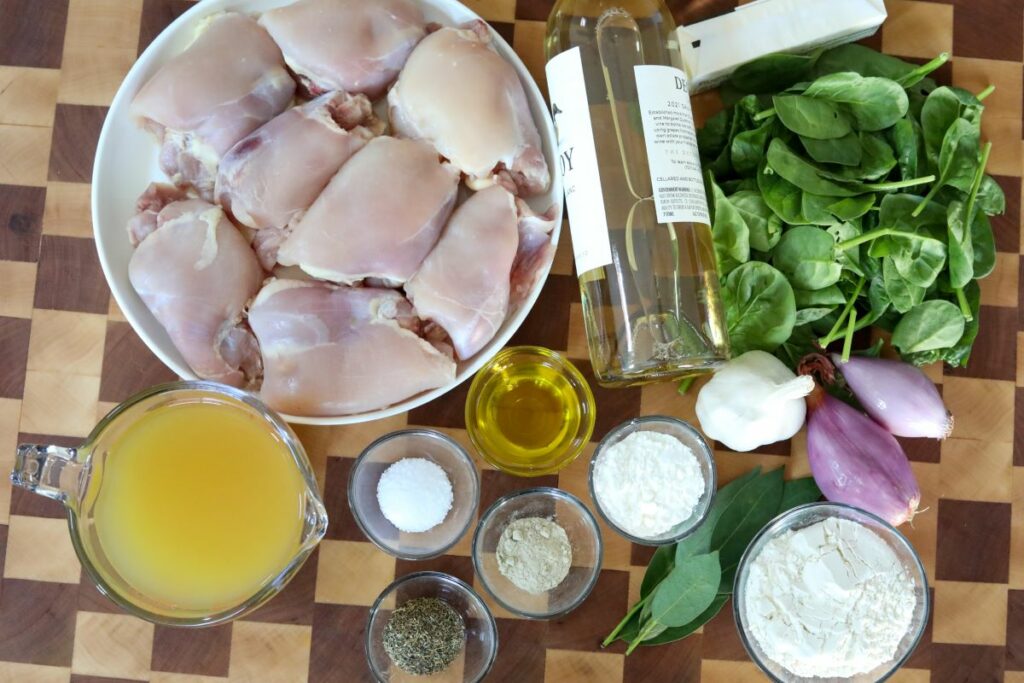 Ingredients for chicken in white wine sauce on a wooden cutting board