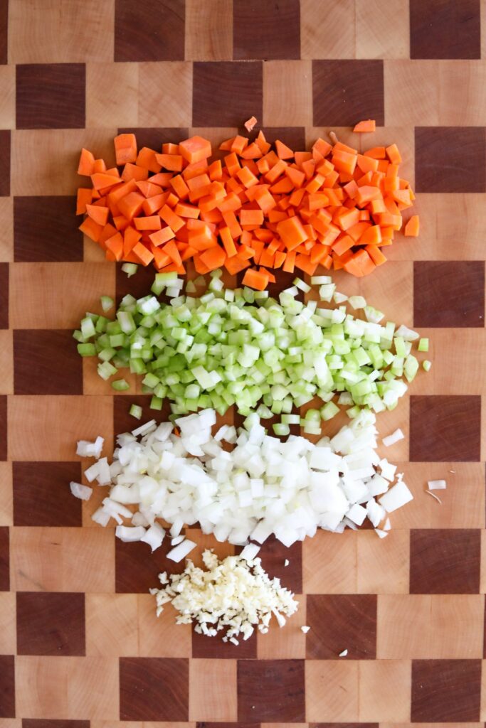 chopped carrots, onions, garlic, and celery on a cupping board