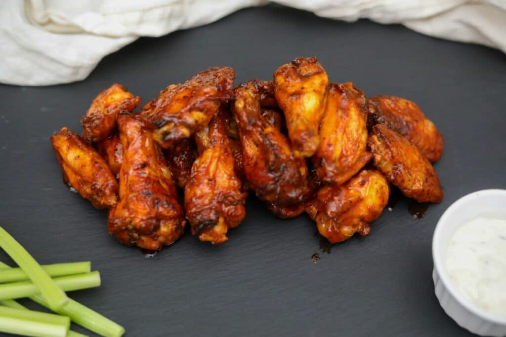Old Bay buffalo wings with dipping sauce and celery on a slate plate