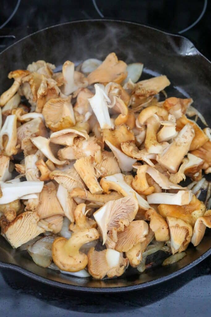 chanterelle mushrooms and onions in a cast iron skillet