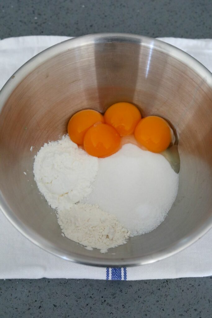 Egg yolks and other ingredients in a metal mixing bowl