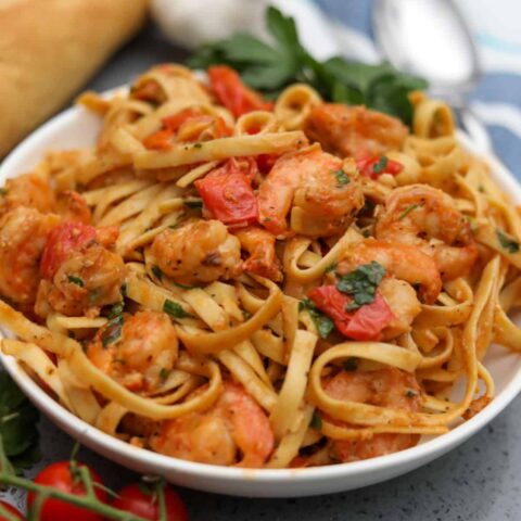tomato and shrimp pasta in a white bowl