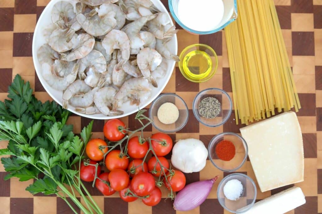 tomato and shrimp pasta ingredients on a wooden cutting board