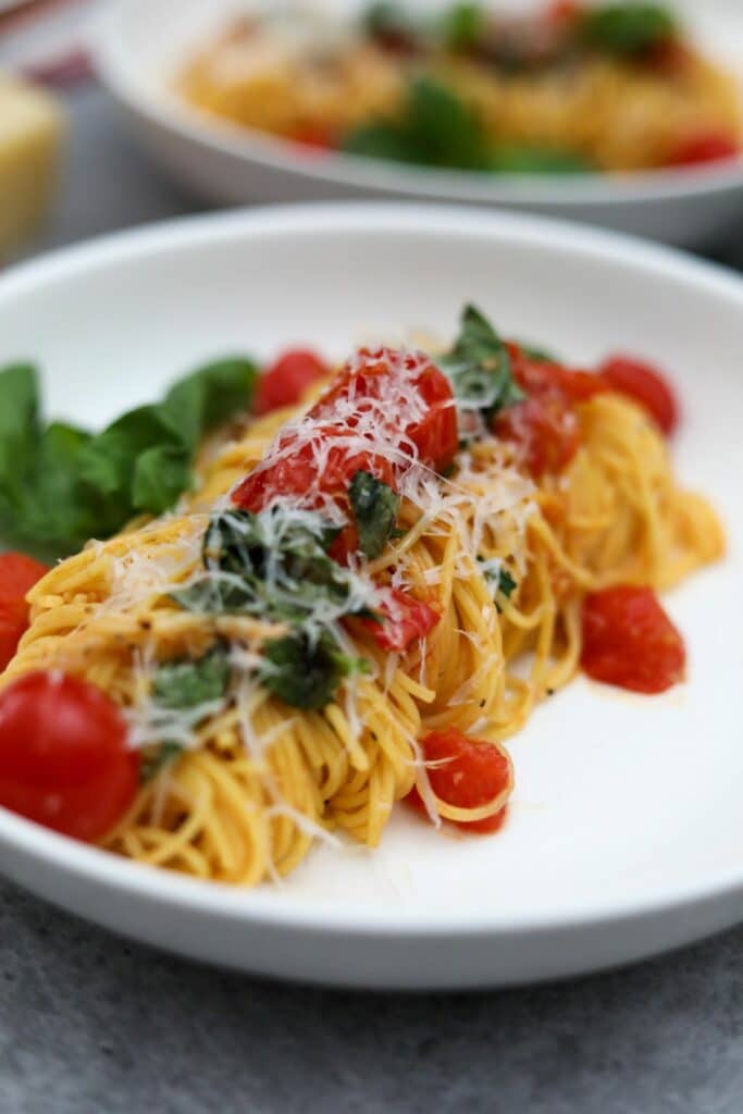 A bowl of angel hair pasta with tomatoes and basil