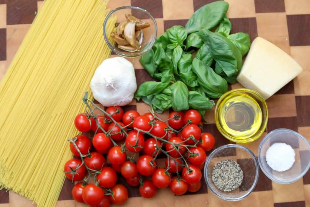 Ingredients for angel hair pasta on a wooden cutting board