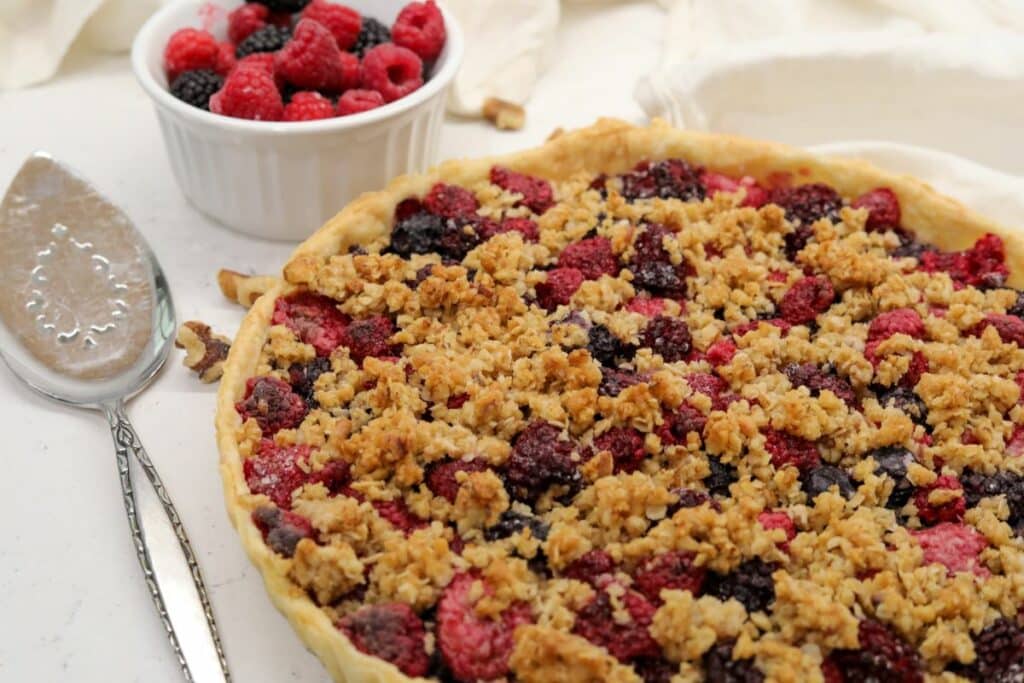 Berry tart with a bowl of fresh berries