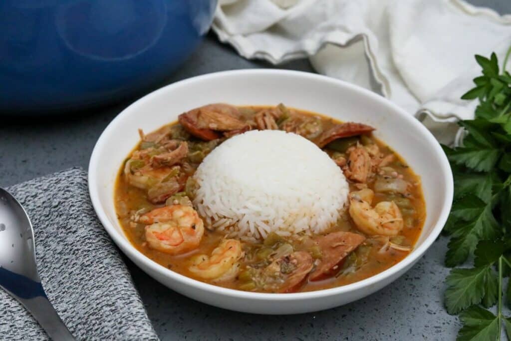 A white bowl with gumbo and a mound of rice