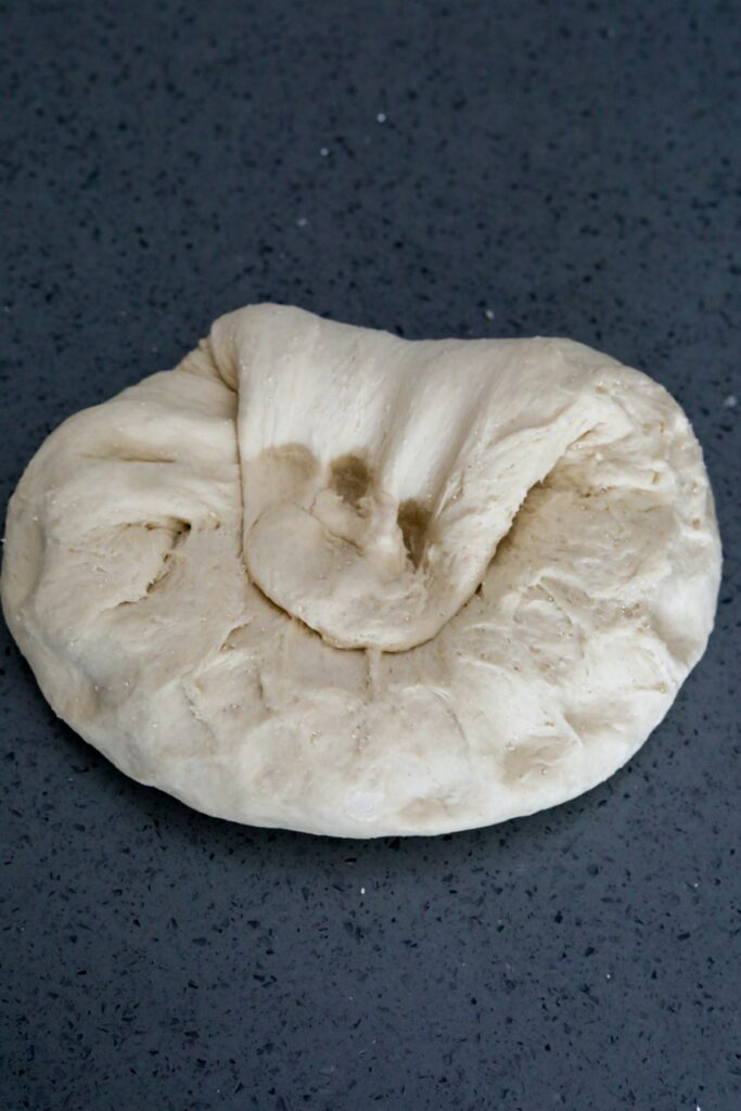Pressing the second stretch back into the dough ball