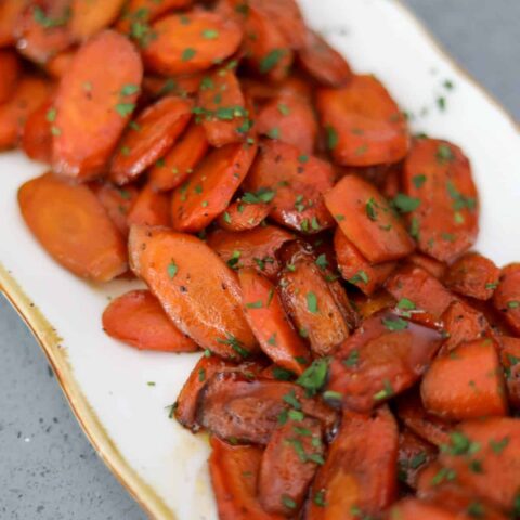 glazed carrots on a gold and white platter