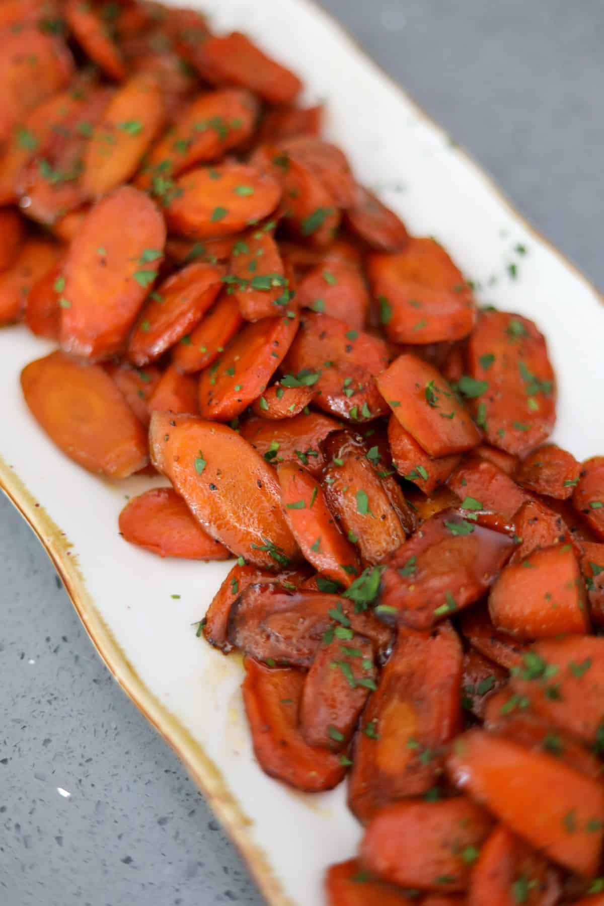 glazed carrots on a gold and white platter