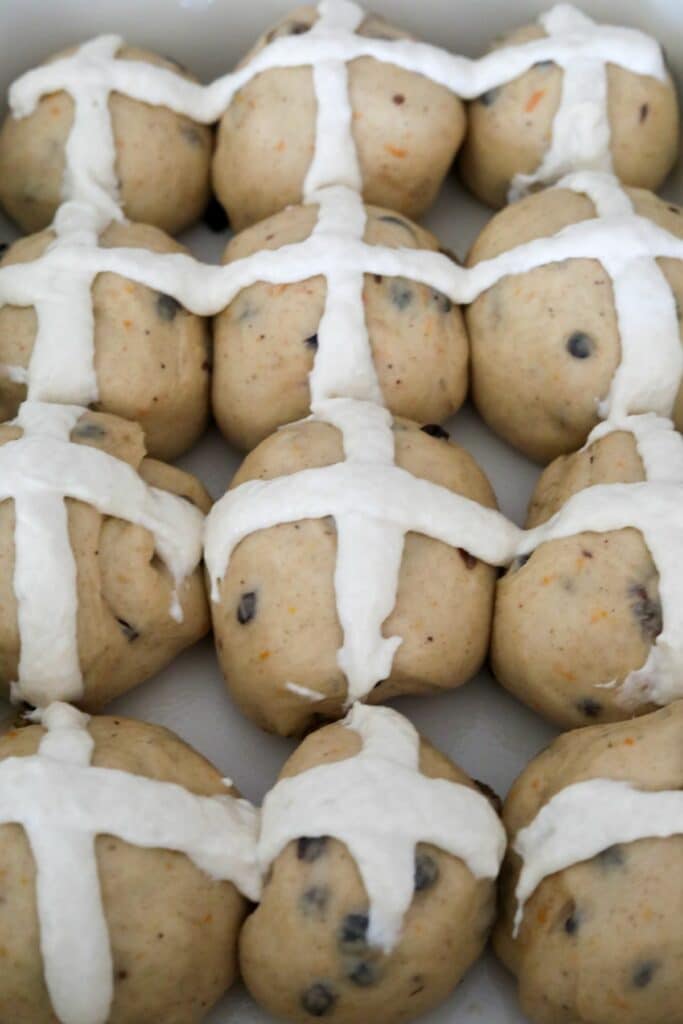 Cross on risen buns in a baking dish