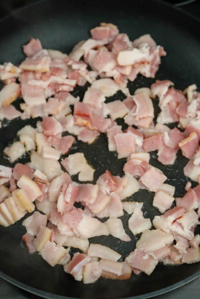 Uncooked cubed bacon in a pan