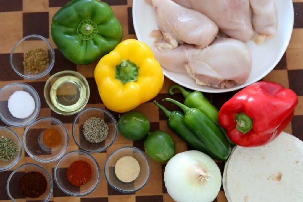 Ingredients for chicken fajitas on a wooden cutting board