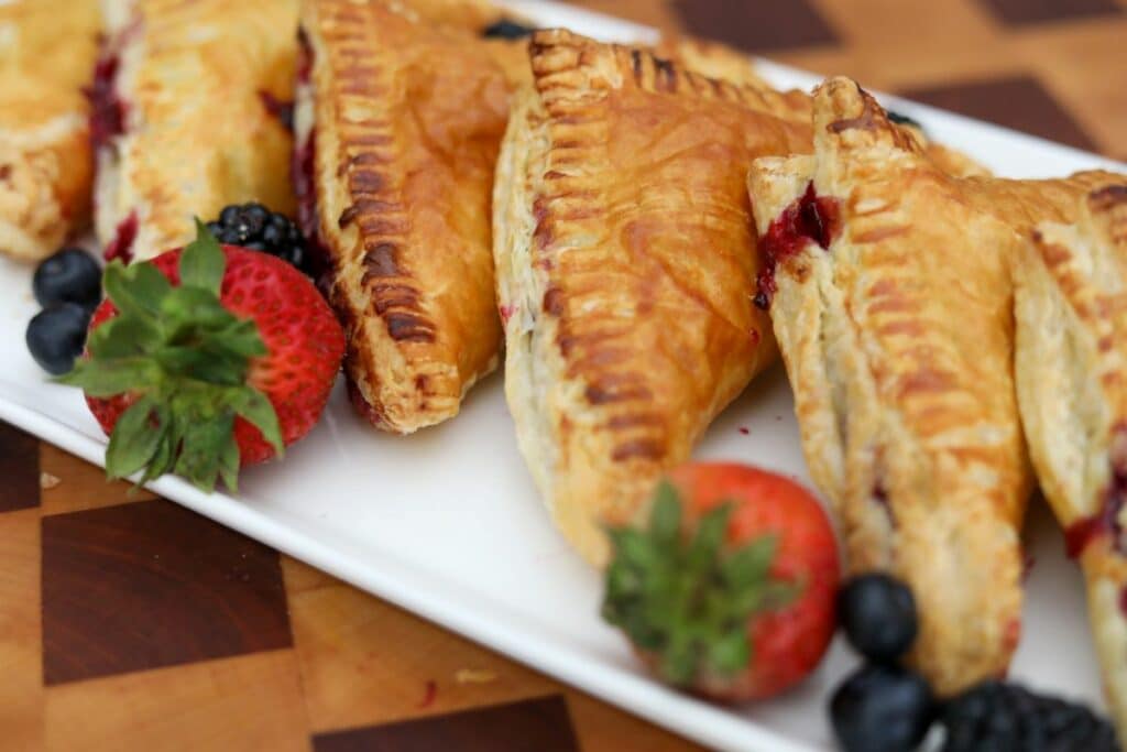 A white platter with berry turnover and fresh fruit