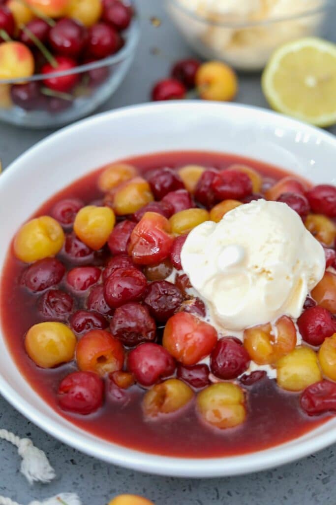 cherries jubilee in a white bowl with ice cream