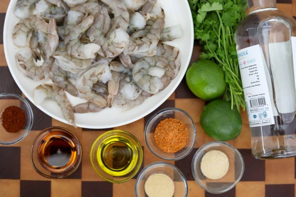 Ingredients for tequila lime shrimp on a wooden cutting board