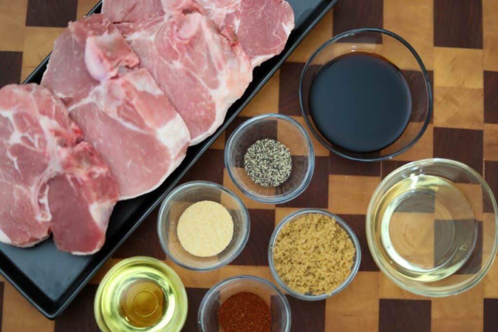 Ingredients for grilled pork chops on a wooden cutting board