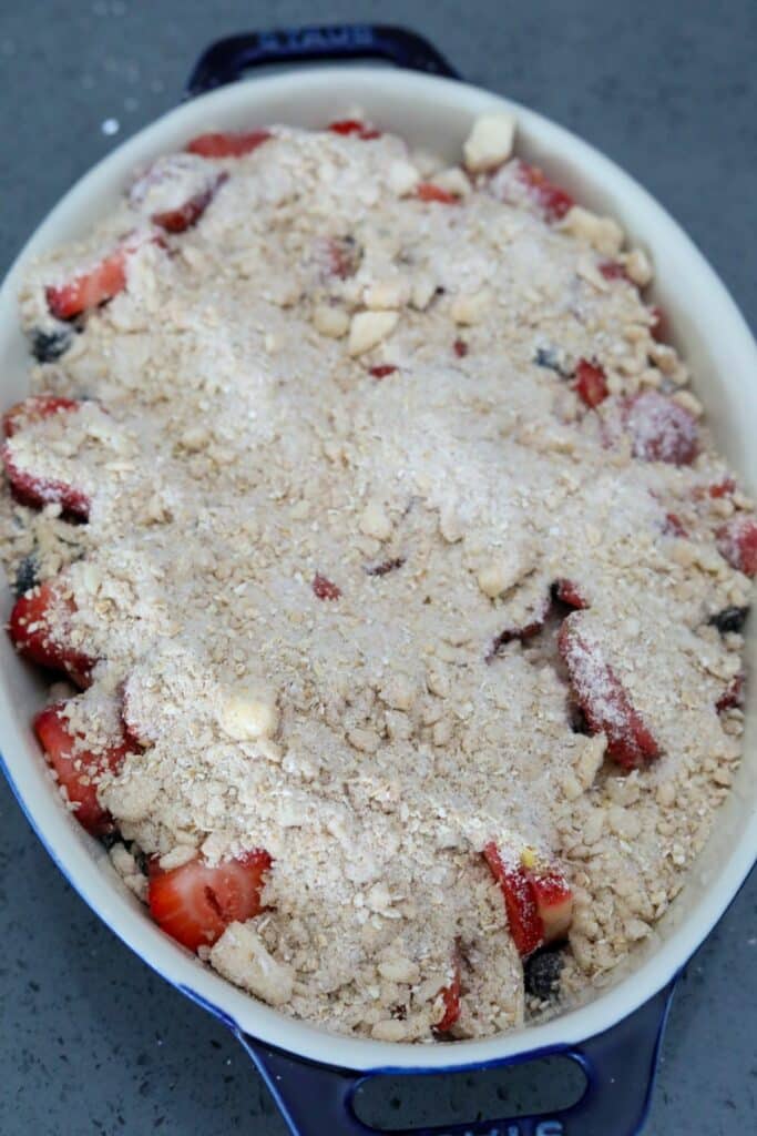 Unbaked strawberry and blueberry crisp in a blue baking dish