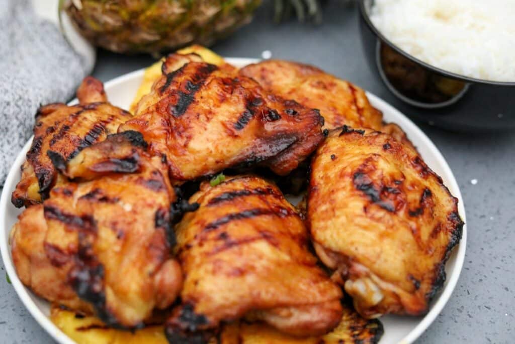 A white dish with pineapple and grilled chicken