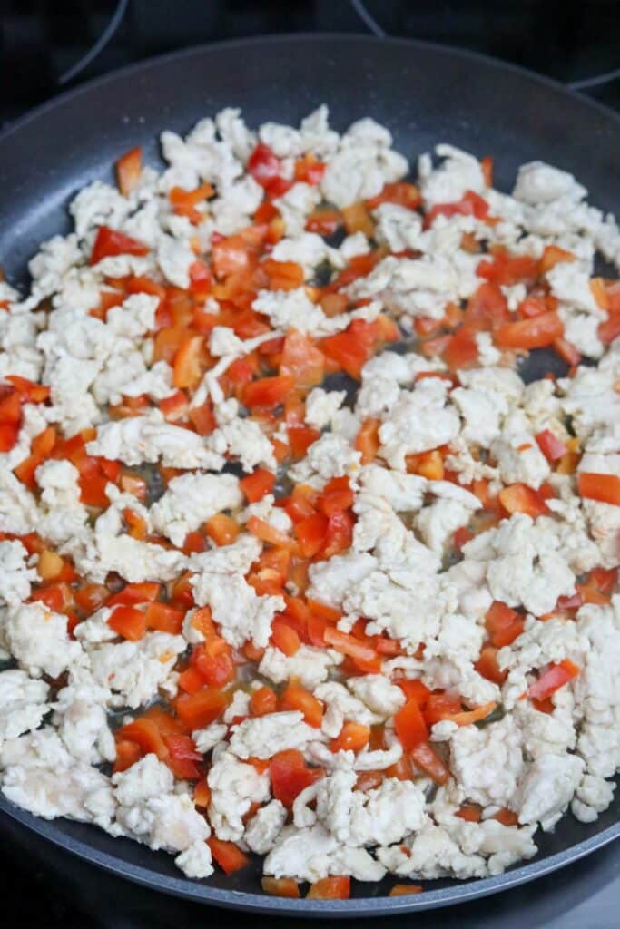 Bell peppers added to ground chicken in a pan